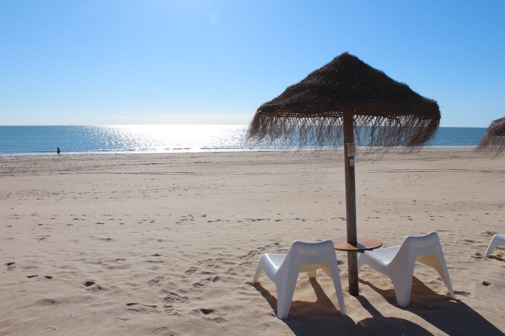 Playa de Rota con sombrilla de paja y sillas mirando al Atlántico